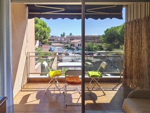 A balcony with two chairs, a table, and a view of a parking area and buildings. - Il Nido by Interhome (Sanremo)