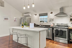 Een moderne keuken met een centraal eiland, roestvrijstalen apparatuur en een barkruk.