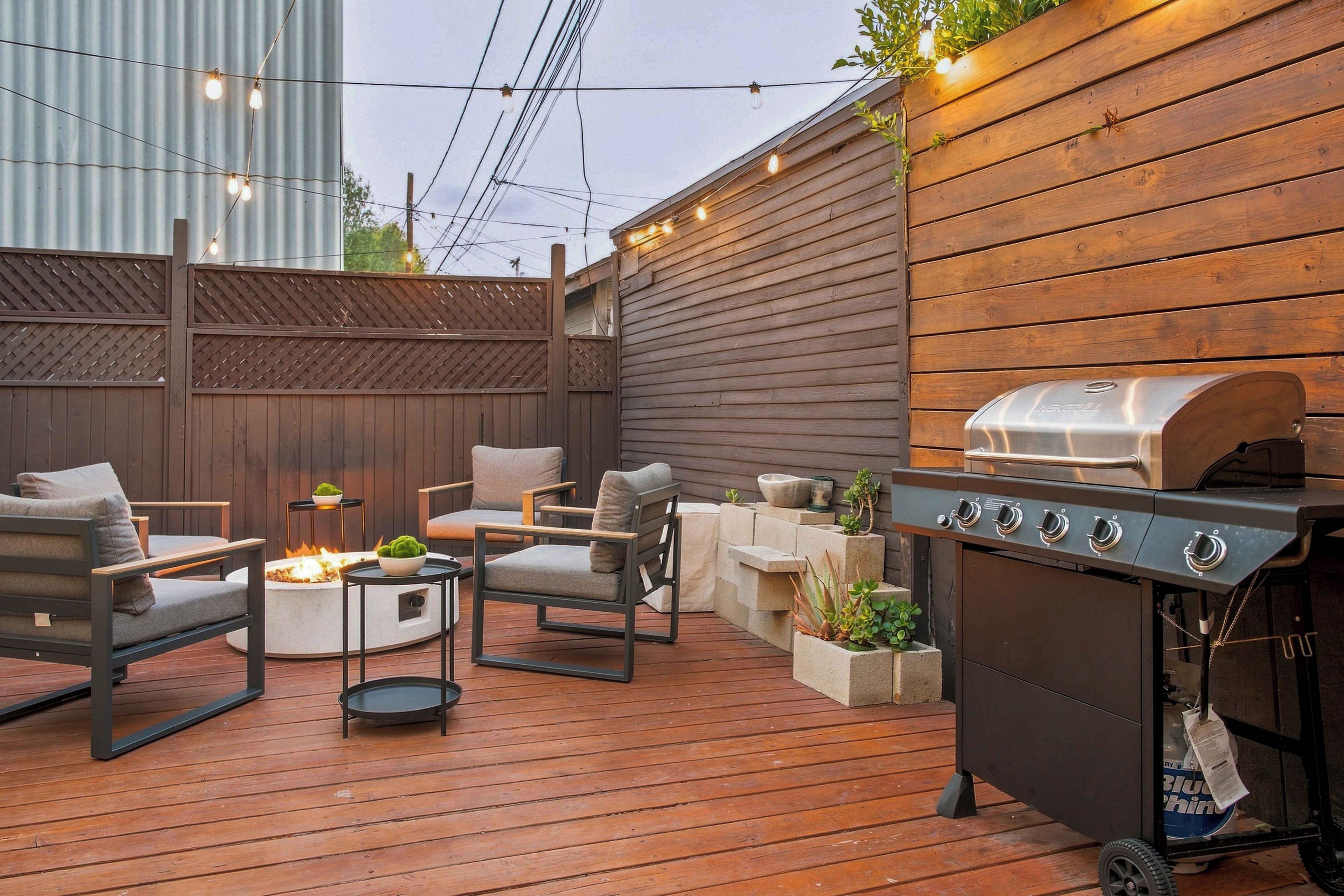 Ein Garten mit Grill, Sitzgelegenheiten im Freien und einer Feuerstelle.