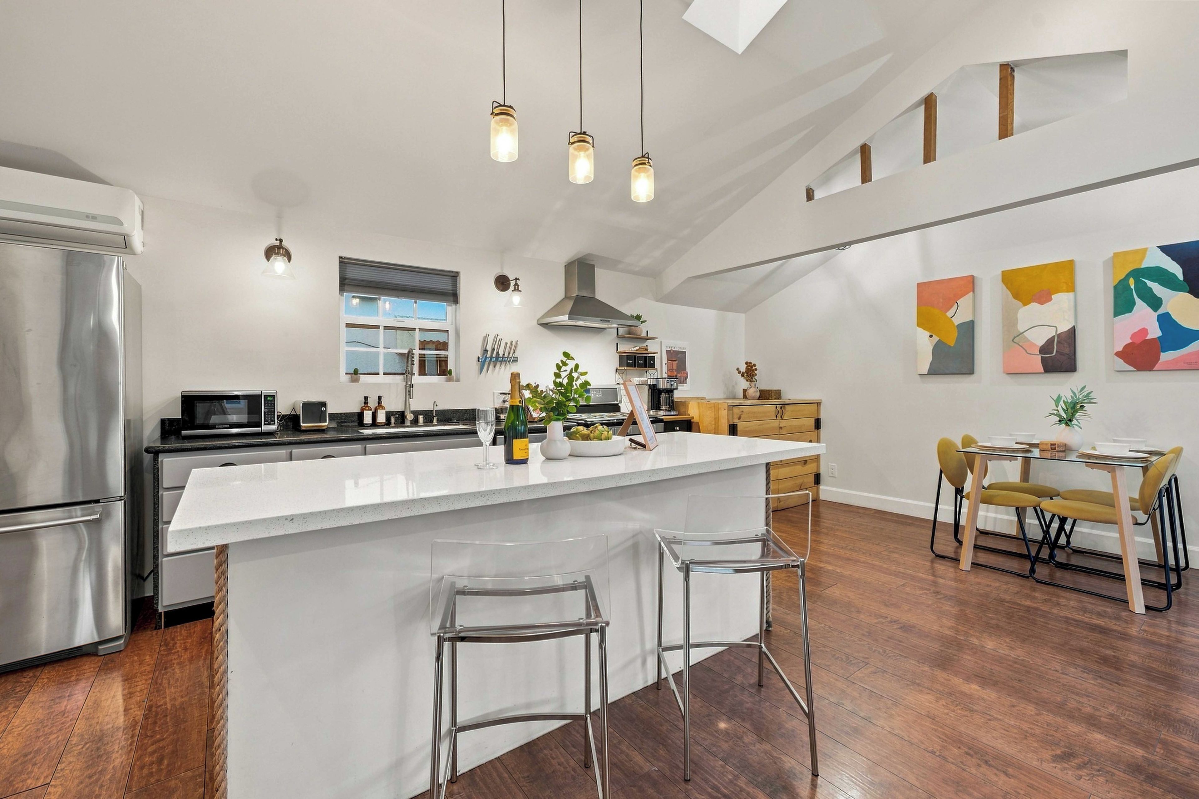 A modern kitchen with a central island, stainless steel appliances, and a dining area with a table and chairs.