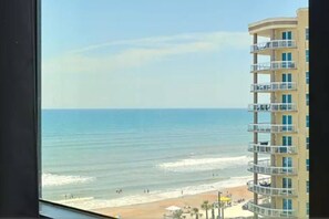 Vista de uma praia com um edifício alto ao fundo.