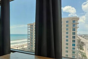 A view of a beachside building with multiple floors and balconies, overlooking the ocean. - Top floor corner oceanview panoramic studio w/pool (Daytona Beach)