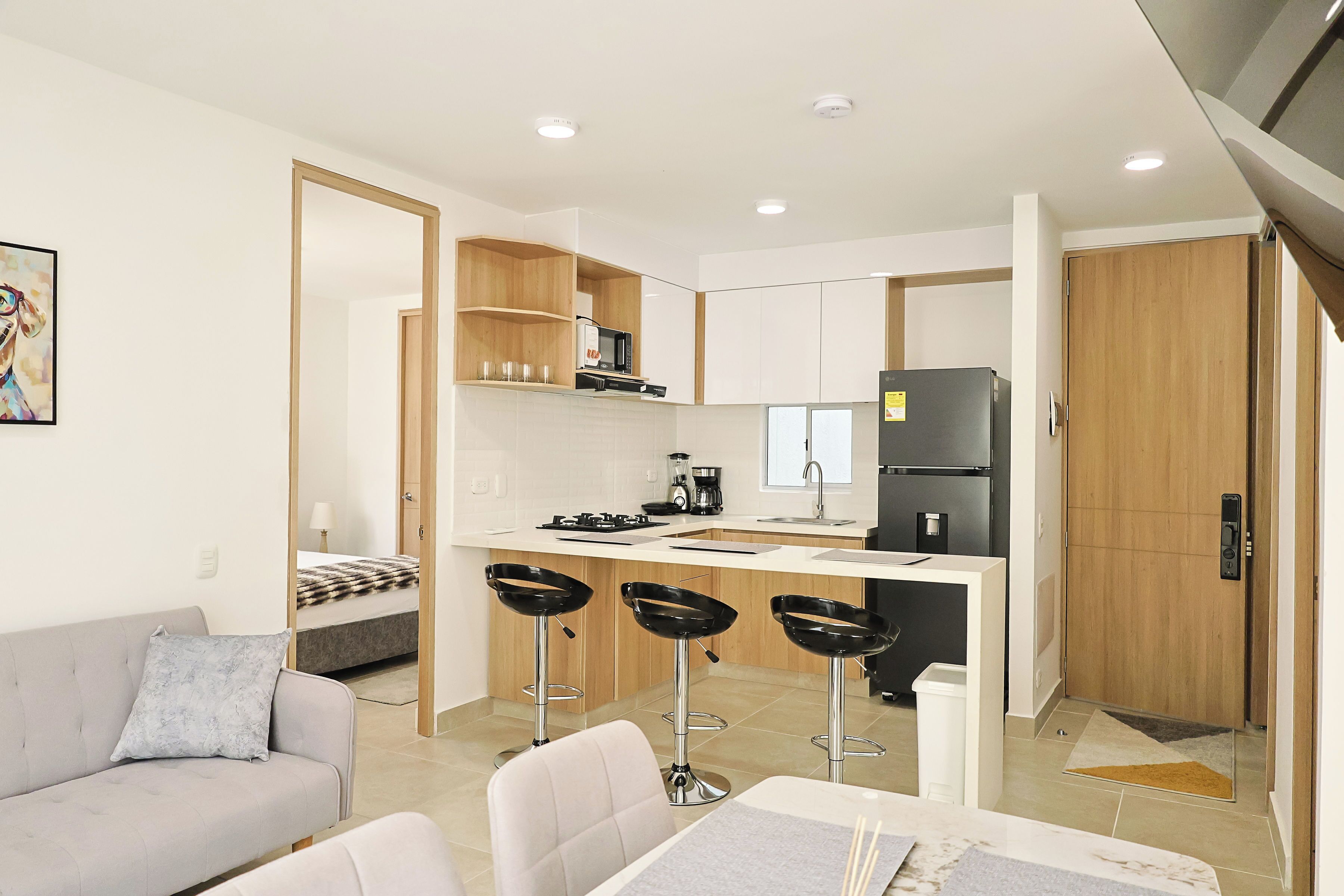 Eine moderne Wohnung mit einer Küchenzeile, einem Essbereich mit Barhocker, einer Couch und einem Bett.