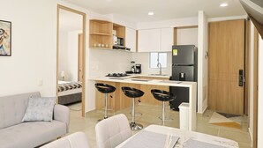 Um apartamento moderno com cozinha compacta, área de refeições com banquetas, sofá e cama.