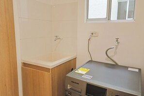 Une salle de bain avec un lavabo blanc, deux robinets, une douche et un pommeau de douche à main.