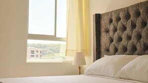 Quarto de hotel com uma cama grande, uma janela com cortinas e vista para edifícios.