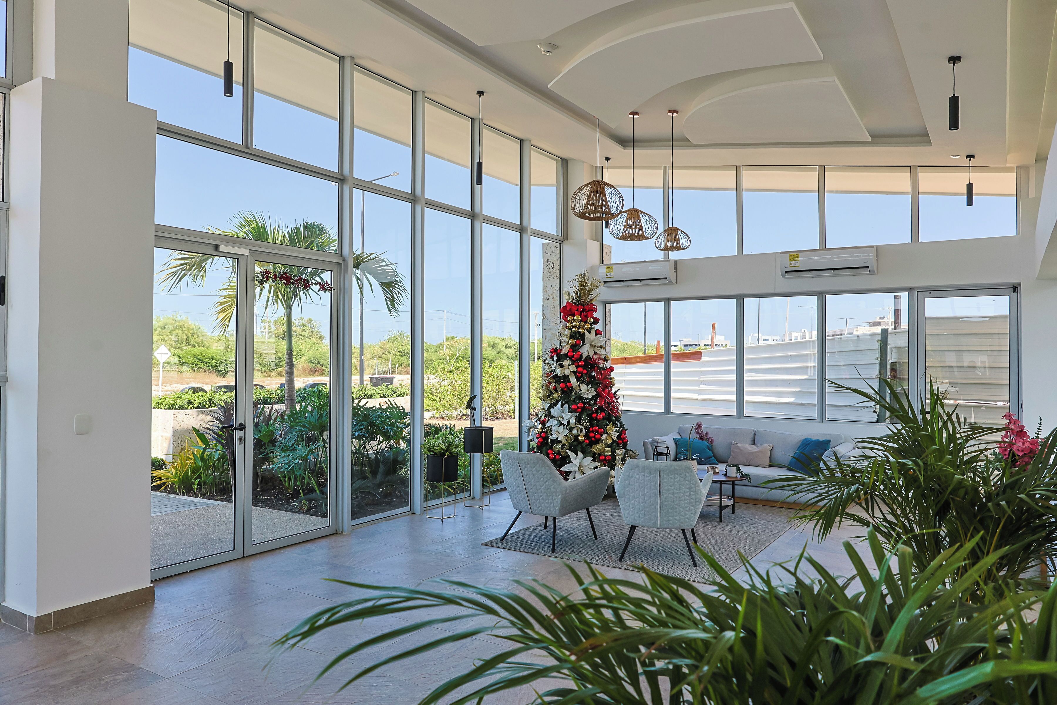 A spacious living area with large windows, a modern ceiling design, and a Christmas tree.