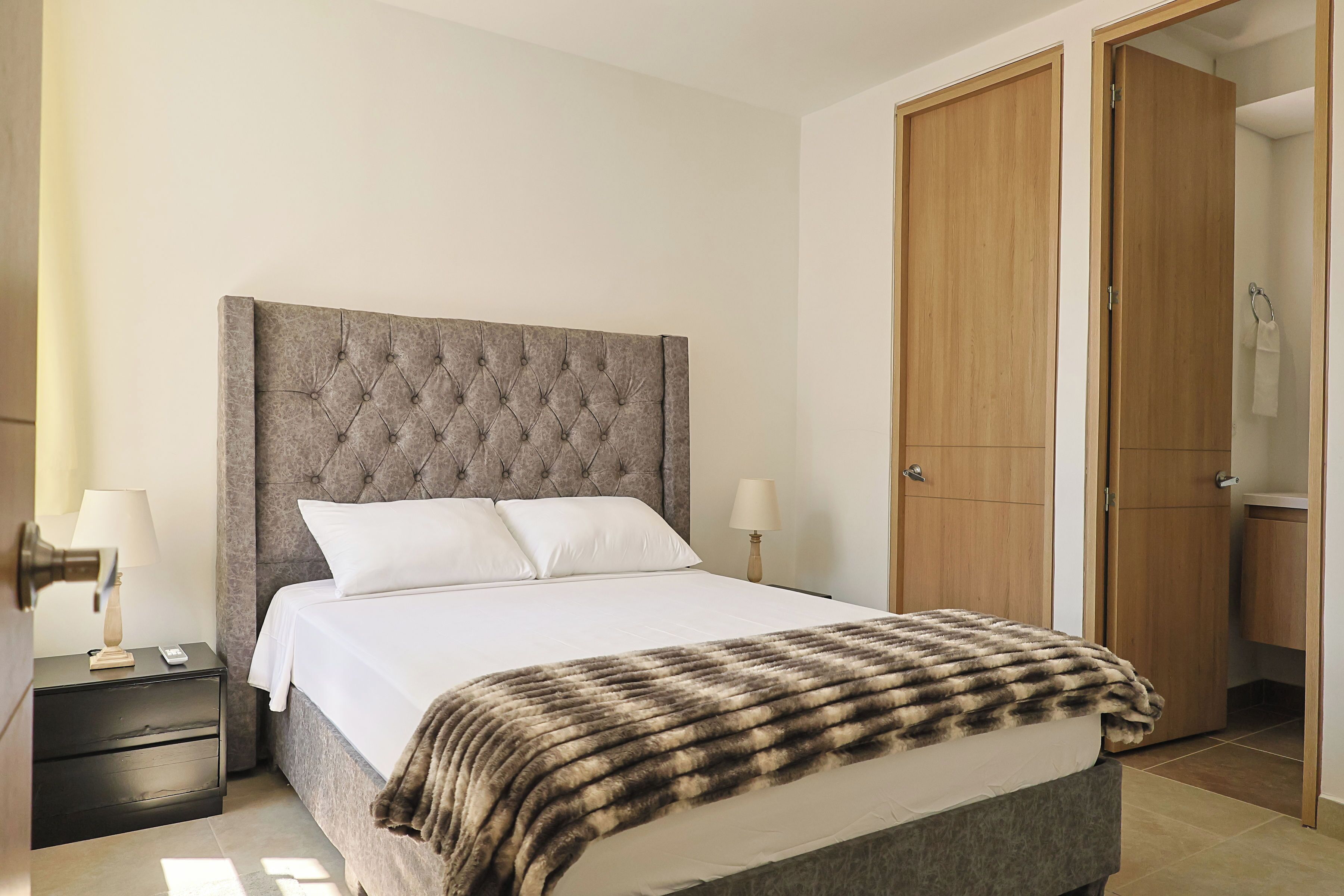 Una camera da letto con un letto grande, due comodini, un armadio in legno e l'ingresso del bagno.