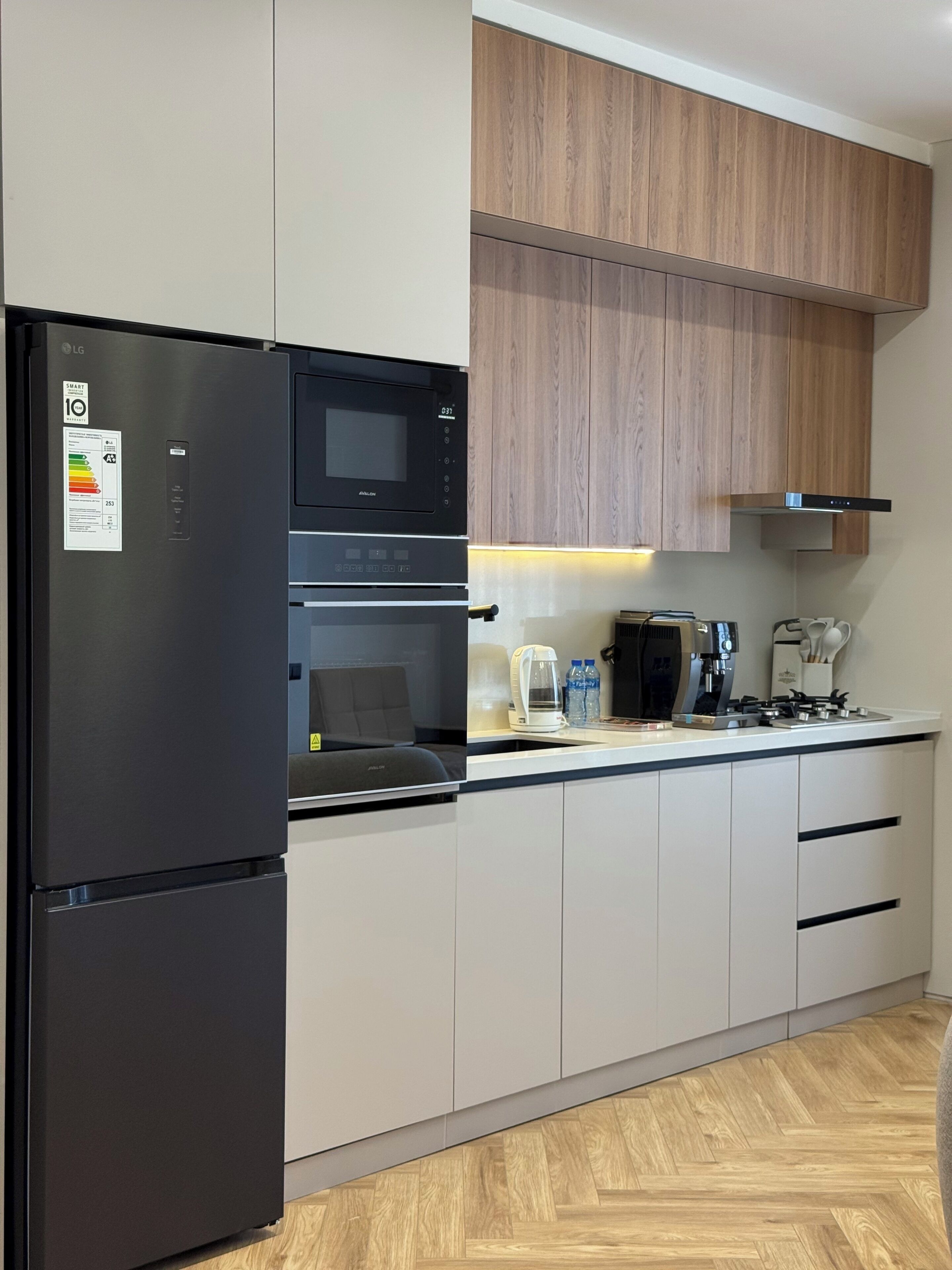 A modern kitchen with a black refrigerator, an oven, a microwave, a coffee maker, and a gas stove.