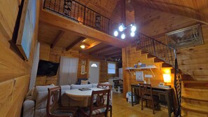 Ein Interieur einer Holzhütte mit Essbereich, einer Couch und einer Treppe.