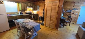 A wooden cabin interior with a kitchen, dining area, and a small living space.