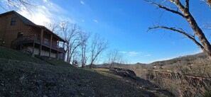 Eine Holzhütte mit Veranda, umgeben von Bäumen und blauem Himmel.