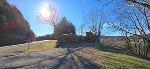 A rural road leading to a wooden cabin with a stone wall entrance.