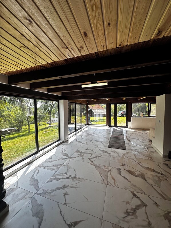 A spacious interior with large windows, a wooden ceiling, and a marble floor.