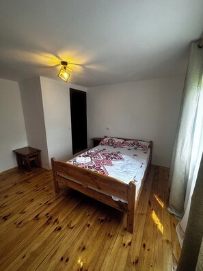 A bedroom with a wooden bed, a small table, and a ceiling light fixture. - House of the SoulCharming 12-bedroom chalet  in Avram Iancu (Avram Iancu)