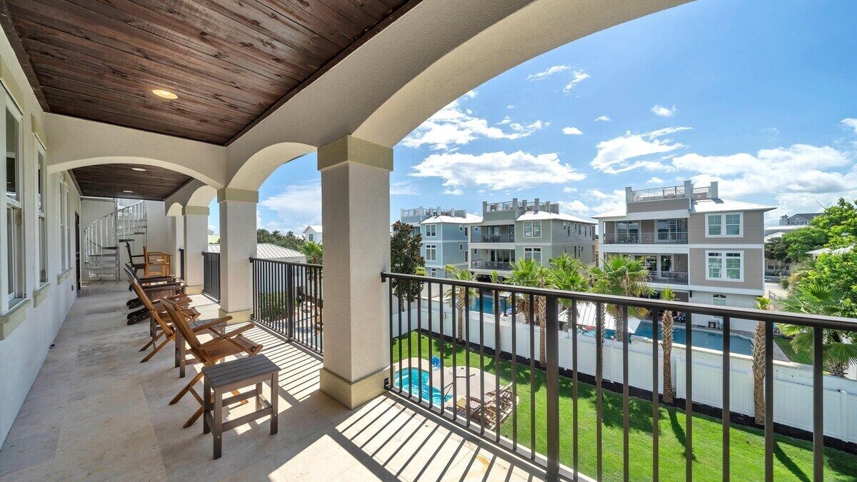 A covered outdoor area with a pool, lounge chairs, and a view of neighboring buildings.