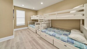 A room with three bunk beds, a window with blinds, and a light-colored floor. - Walking on Sunshine: Golf Cart & Movie Theater! 2 Pools! CLOSE To The Beach! (Destin)