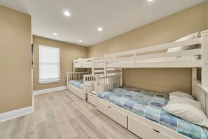 A room with three bunk beds, a window with blinds, and a light-colored floor. - Walking on Sunshine: Golf Cart & Movie Theater! 2 Pools! CLOSE To The Beach! (Destin)