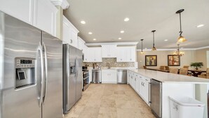 A modern kitchen with stainless steel appliances, white cabinetry, and a central island. - Walking on Sunshine: Golf Cart & Movie Theater! 2 Pools! CLOSE To The Beach! (Destin)