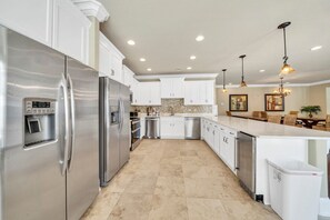 A modern kitchen with stainless steel appliances, white cabinetry, and a central island. - Walking on Sunshine: Golf Cart & Movie Theater! 2 Pools! CLOSE To The Beach! (Destin)