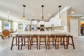 Una cocina amplia con una isla grande, taburetes de bar e iluminación colgante.