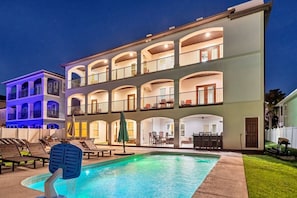Un hotel de varios pisos con piscina, asientos al aire libre y balcones.