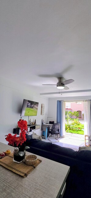 A hotel room with a bed, a desk, a chair, a television, and a ceiling fan. - Ocho Rios Beach Condo-Pool + 3-Min Walk to Beach (Ocho Rios)