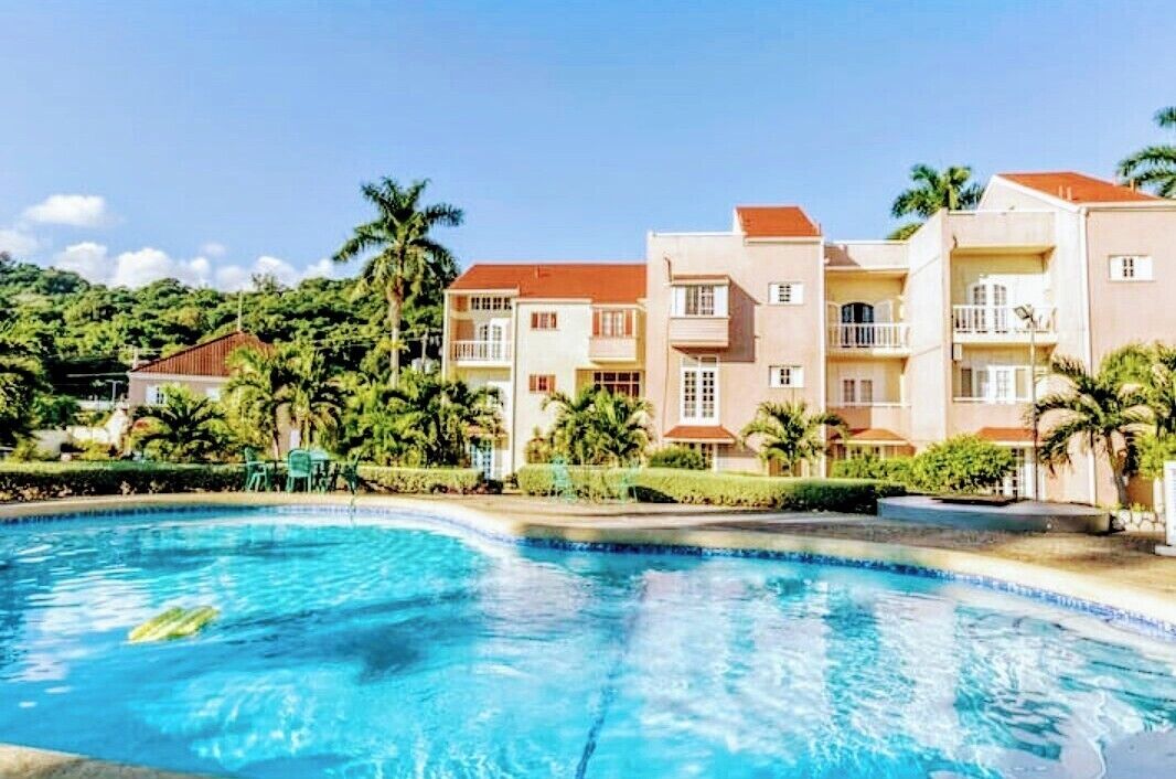 A hotel with a swimming pool, multiple balconies, and lush greenery.