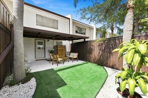 A residential property with a covered patio, a lawn, and a wooden fence.