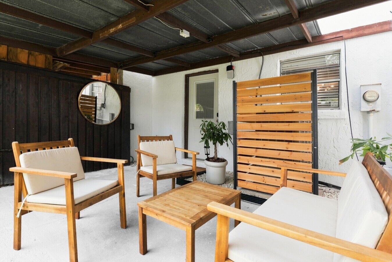 Eine Terrasse mit Holzmöbeln, darunter eine Couch, zwei Stühle und ein kleiner Tisch.