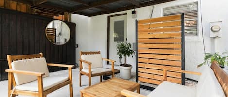 Un patio amueblado con mobiliario de madera, incluyendo un sofá, dos sillones y una mesita.