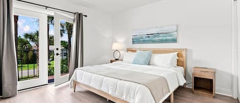 A bedroom with a bed, a nightstand, a ceiling fan, and a view through a sliding glass door.