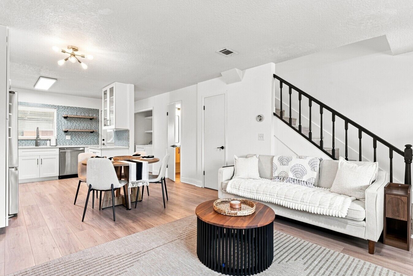 A modern living room with a sofa, coffee table, and dining area.
