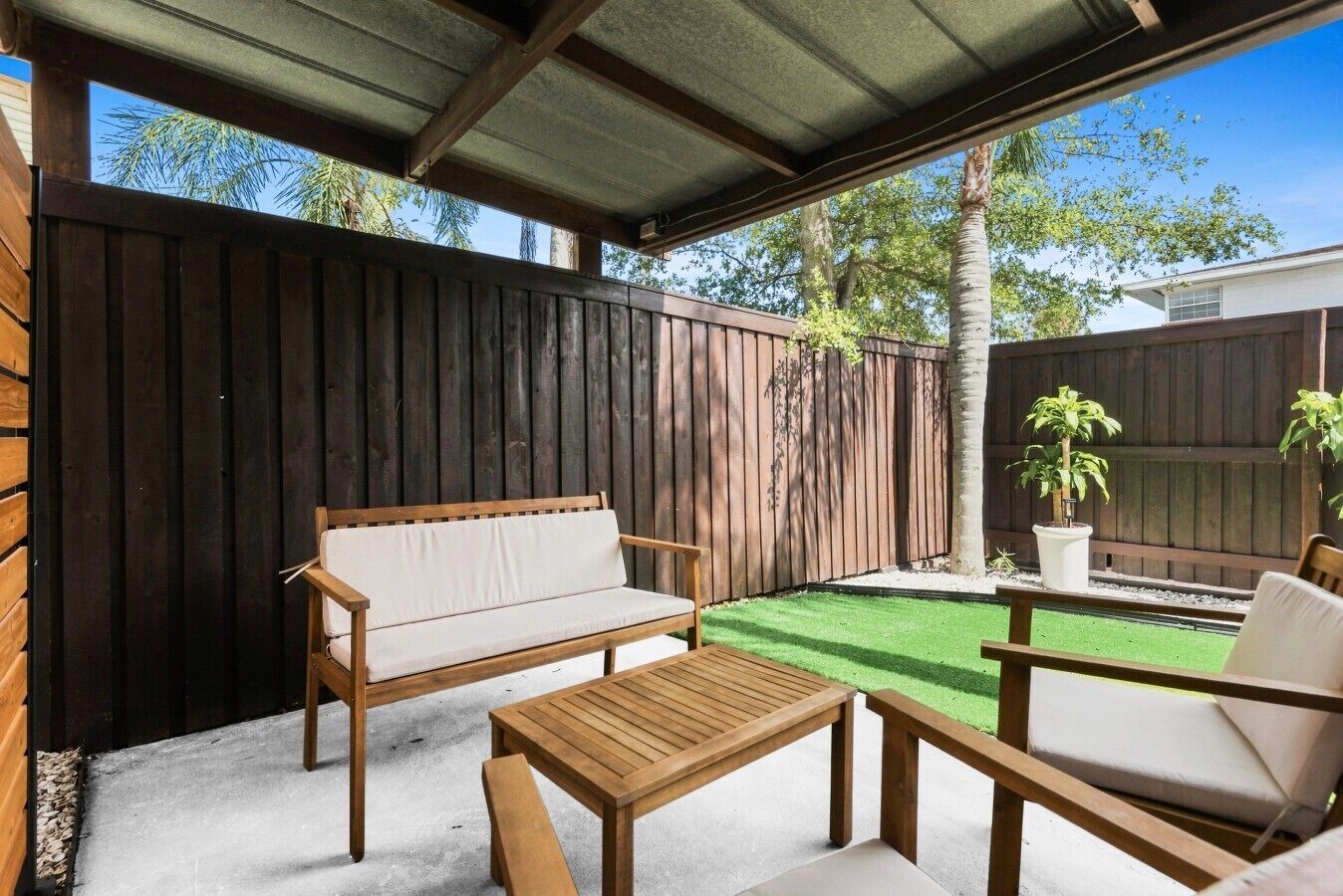 Un patio abrité comprenant un banc en bois, une table et deux chaises.