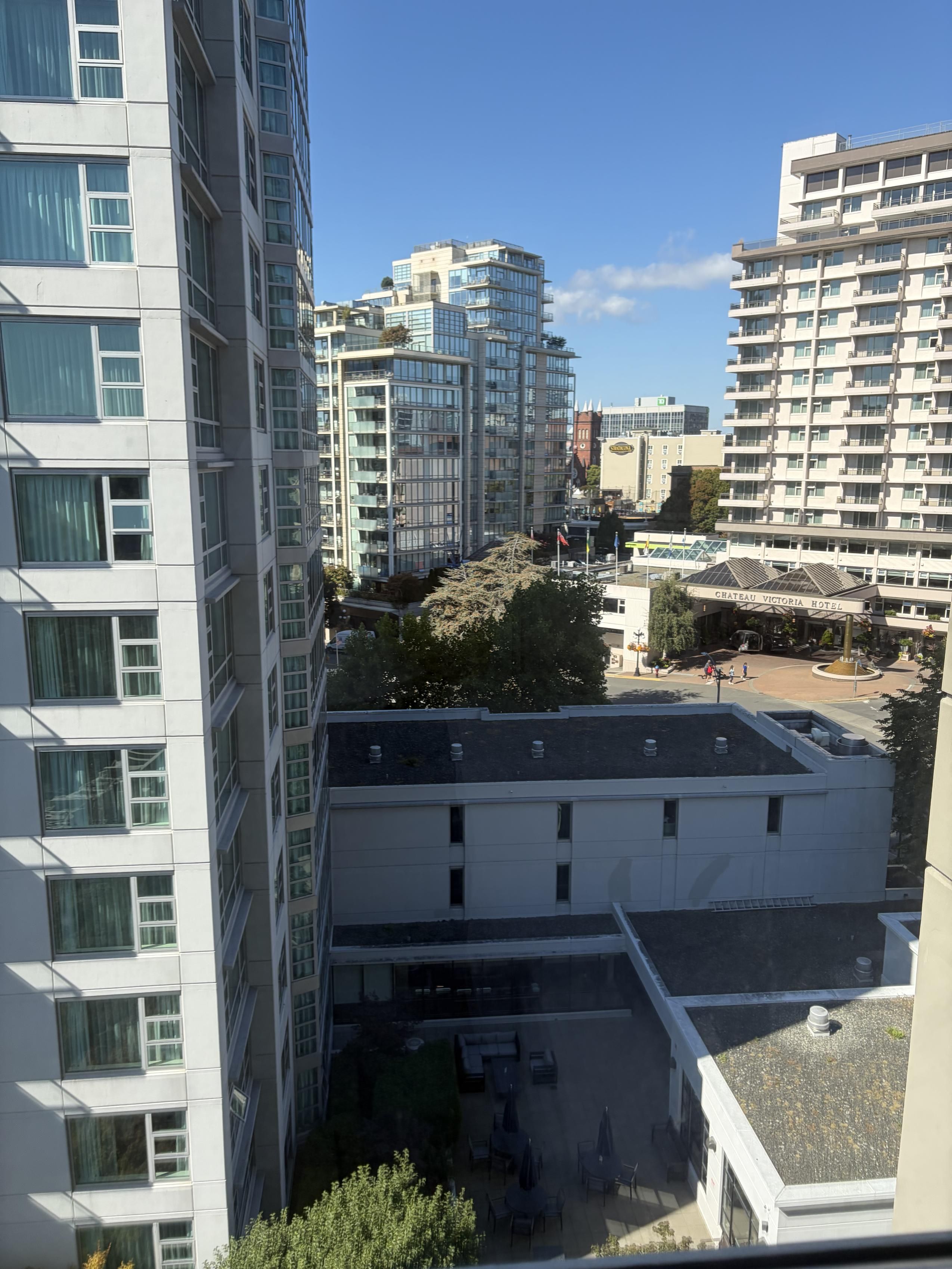 Un hotel de varios pisos con terraza en la azotea y vistas de edificios circundantes.