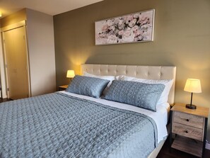 Ein ordentlich bezogenes Bett mit einer gesteppten Decke, einem gepolsterten Kopfteil und zwei Nachttischlampen.