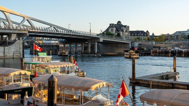 Uma área à beira-mar com uma ponte, barcos e um edifício histórico.