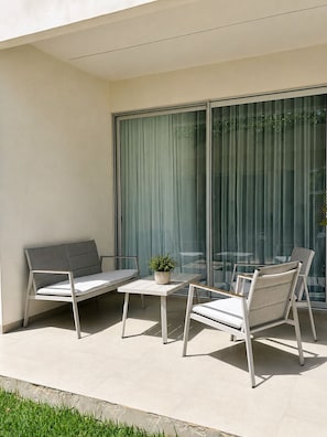 Ein Balkon mit einer Couch, zwei Stühlen, einem kleinen Tisch und einem Blumentopf.