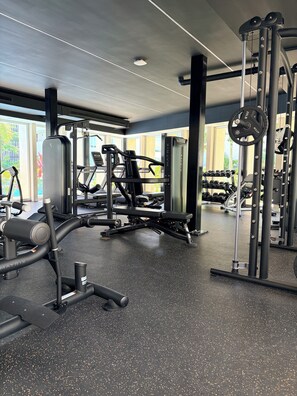 Een sportschool met diverse fitnessapparaten, waaronder een loopband, krachttoestellen en gewichten.
