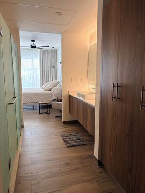 Ein Hotelzimmer mit Bett, Nachttisch und einem Badezimmer mit Spiegel und Waschbecken.