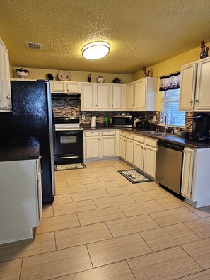 A kitchen with white cabinets, a black refrigerator, a microwave, and a dishwasher. - 3-bedroom house in welcoming Mesquite with cool AC (Mesquite)