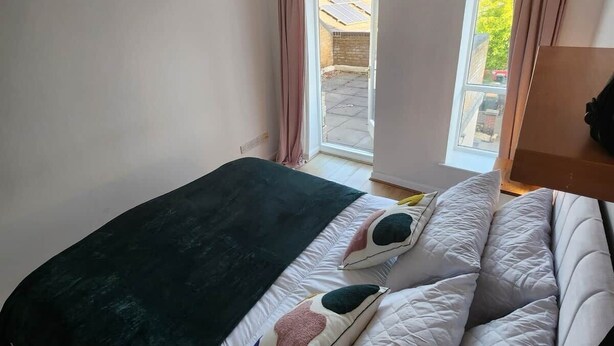 A bedroom with a bed, a window with curtains, and a hanging lamp. - Modern Bright Riverside Stay (London)