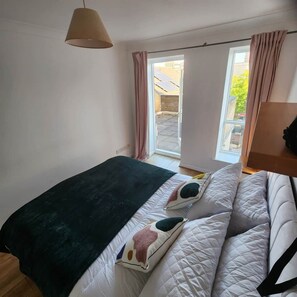 A bedroom with a bed, a window with curtains, and a hanging lamp. - Modern Bright Riverside Stay (London)