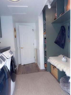 Ein Waschraum mit Waschmaschine, Trockner und einer Tür zu einem anderen Zimmer.