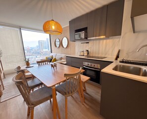 Eine moderne Küche mit Essbereich, großen Fenstern und Blick auf die Stadt.