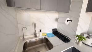 A modern kitchen with a stainless steel sink, a faucet, a soap dispenser, a sponge holder, and a toaster. - Santiago Metro Ecuador - Domus Travels (Santiago)