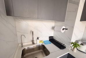 A modern kitchen with a stainless steel sink, a faucet, a soap dispenser, a sponge holder, and a toaster. - Santiago Metro Ecuador - Domus Travels (Santiago)