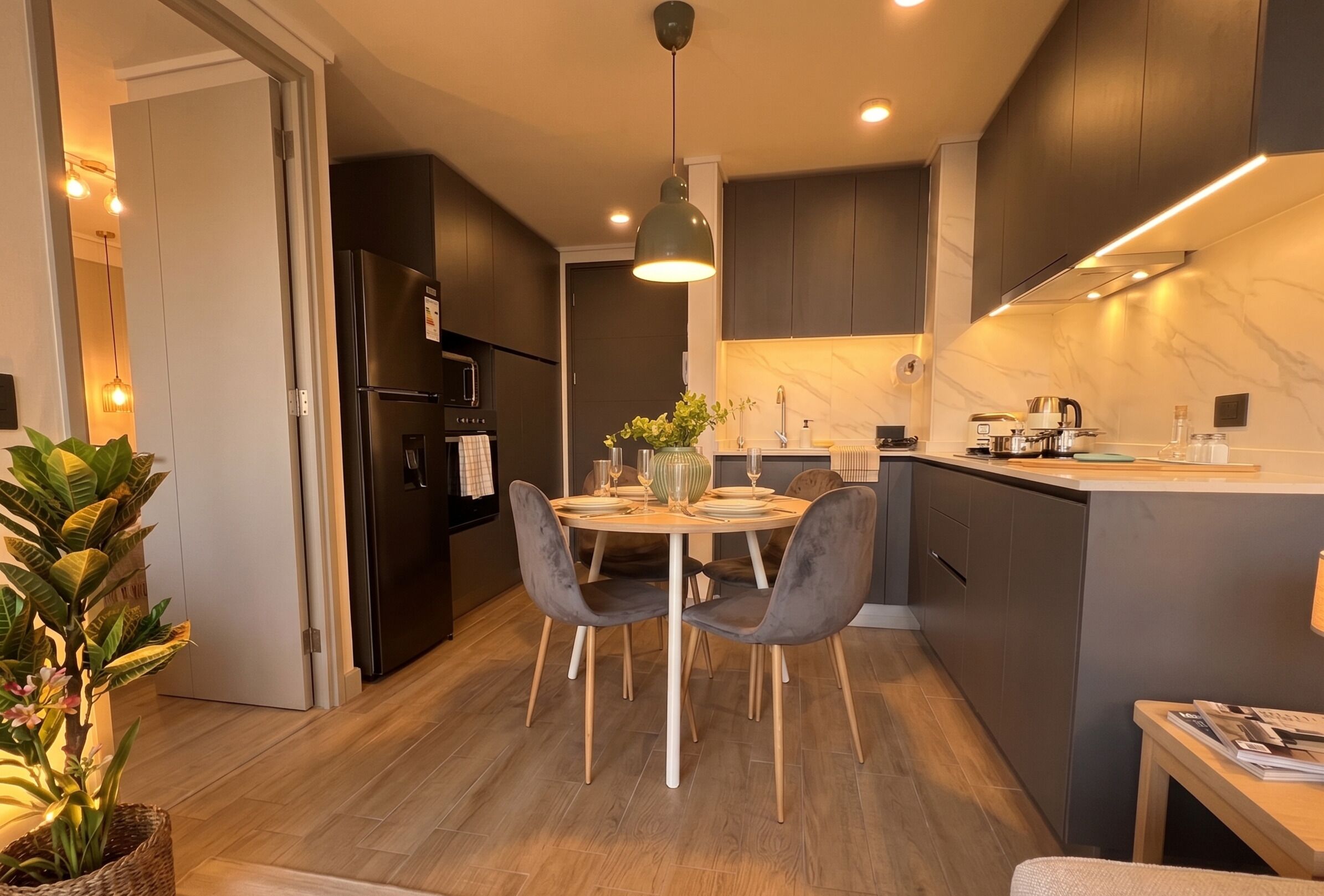 A modern kitchen with dark cabinetry, a central island, and a dining area with two chairs.