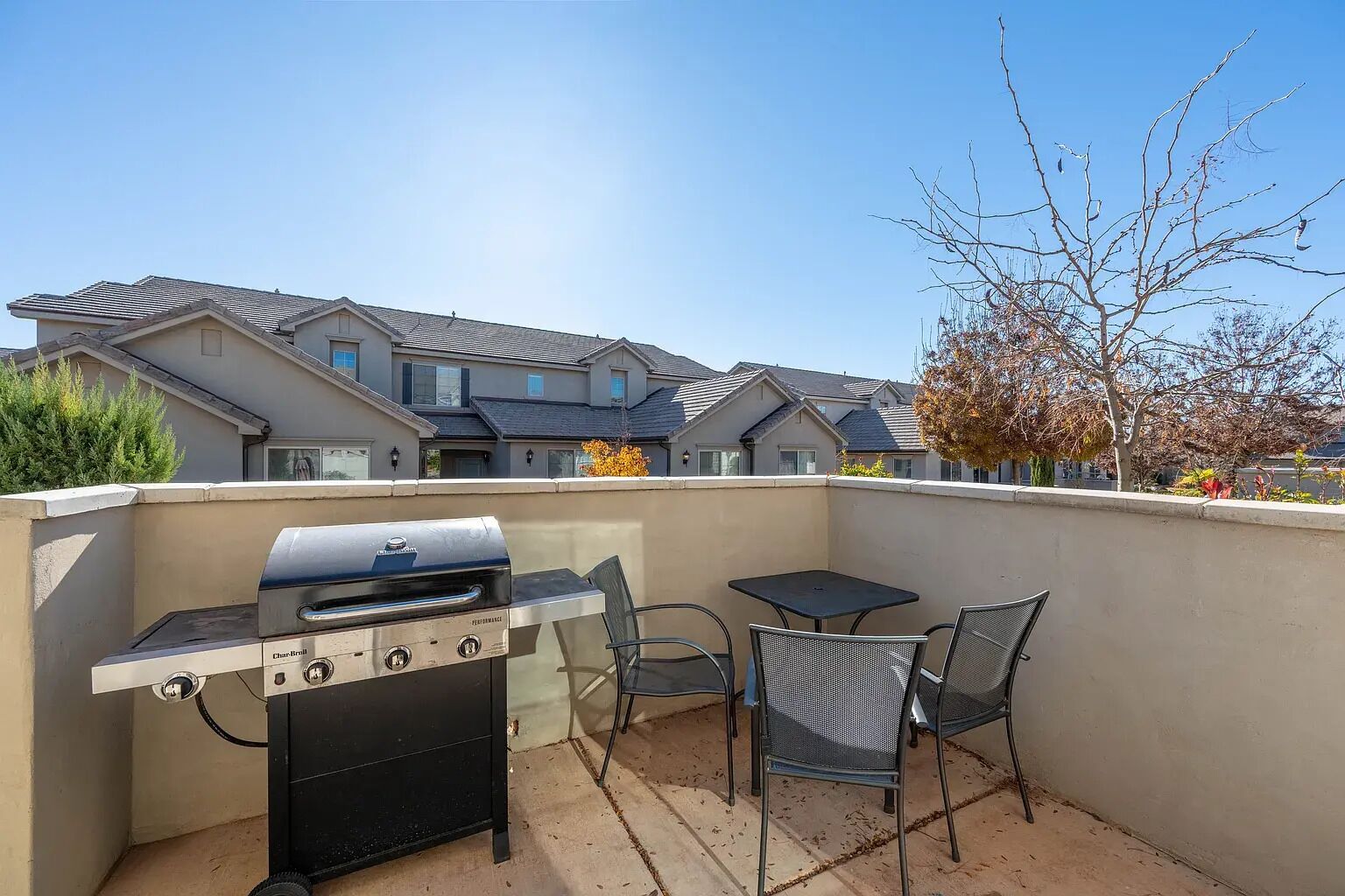 Un patio al aire libre con una parrilla, dos sillas y una mesa.