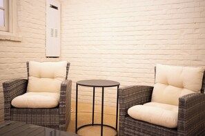 Two wicker chairs with cushions, a small round table, and a white brick wall. - 3 King Beds with En Suite Bathrooms and Private Shuttle to Square & Stadium (Oxford)